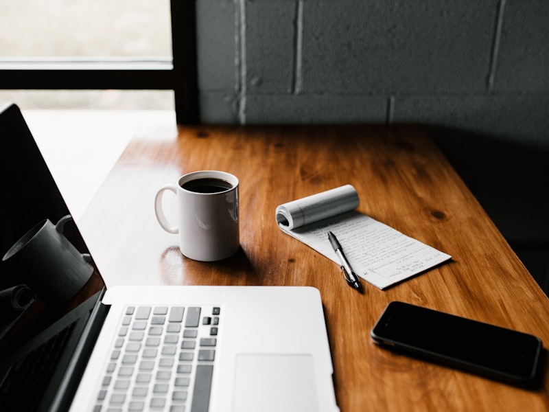 A laptop, coffee and notepad on a desk